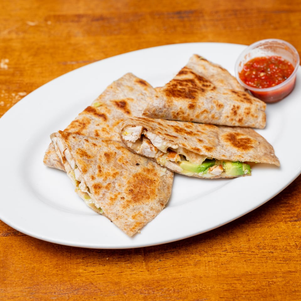 Chicken and avocado quesadillas with melted cheese on a white plate, served with a side of salsa.